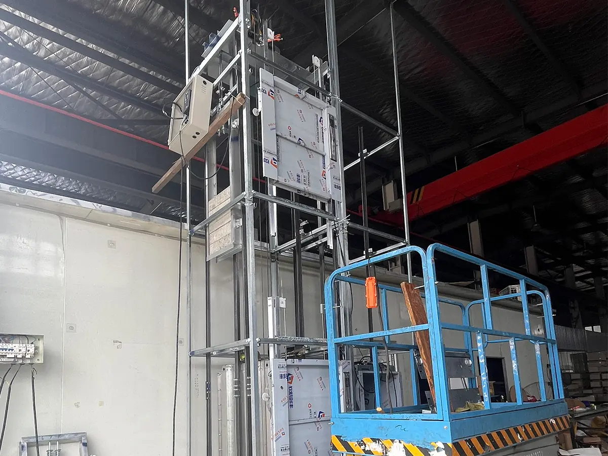 Engineer inspecting a commercial dumbwaiter during factory quality testing before export